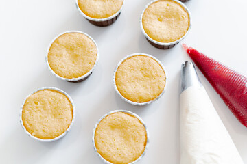 freshly baked cupcakes on a white table, next to the cooking sleeves with red strawberry berry filling and white cream cheese.Food for breakfast. Freshly baked cupcakes for dessert.
