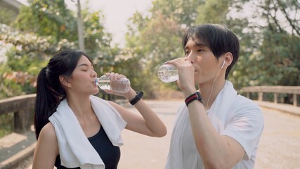 Young Asian couple resting and relaxing after run in out door park talking , smiling and laughing together. Sweet couple have romantic concept.