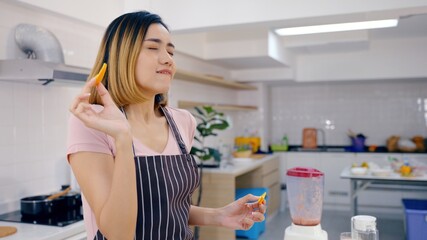 Portrait Asian young happy beautiful Woman eating spoon of fruit smoothie in the kitchen. female emotion making a very sour expression. Healthy lifestyle concept.