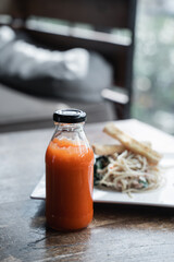 a bottle of chilli sauce served with the appetizer in the background of the restaurant
