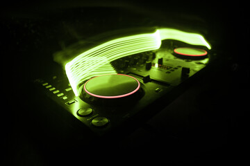 DJ console deejay-mixing desk in dark with colorful light. Mixer equipment entertainment DJ station.