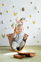 Cute young toddler boy wearing a bunny rabbit costume looking on a carrot sitting in a flower pot. Happy Easter time