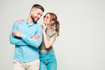 Smiling beautiful woman and her handsome boyfriend. Happy cheerful family having tender moments.Posing on grey background in studio.Pure models hugging in sunglasses.Embracing each other.Love concept