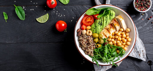 Buddha bowl with kale salad, quinoa, chicken fillet, chickpeas, avocado, spinach, tomatoes cherries, nuts arugula, Clean eating, dieting food concept. Long banner format. top view