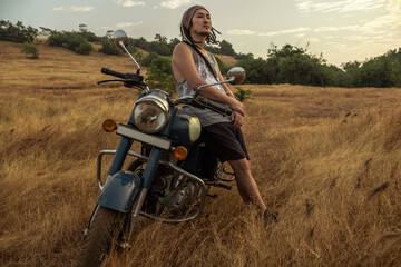 Fototapeta na wymiar A man stands near a motorcycle in a field