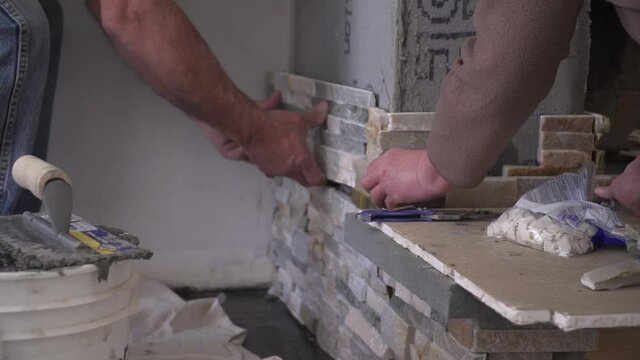 Male Hands Setting Stacked Stone Tiles for a Fireplace