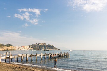 Fototapeta na wymiar Ponton en bois sur la plage sur l'île de Procida en Italie dans la baie de Naples. Une magnifique destination touristique