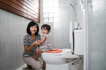 the smile of a baby pup and a woman looking at the camera against the background of the toilet in the bathroom