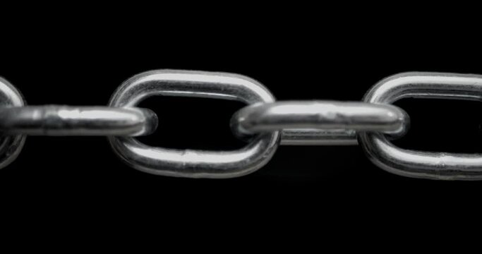 Slow panning across a shiny steel chain showing each link pulled taut. Concept of strength, security, or strong connection.