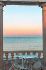 a white rotunda with tables and chairs. Sea view