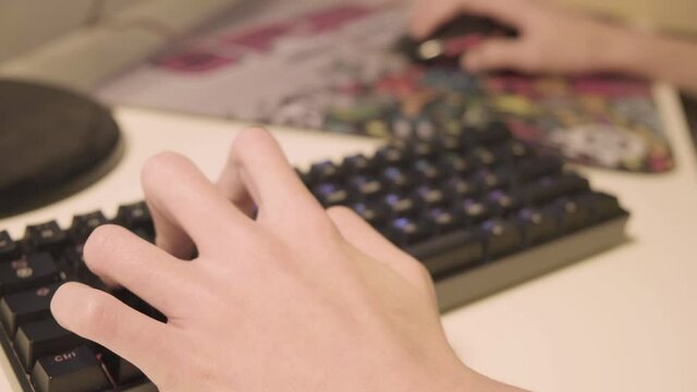 close up of hands playing computer games. Professional eSports Gamer kid Plays Fortnite Game with Super Action and Fun Special Effects on His Personal Computer.
