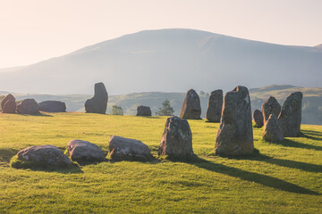Golden sunrise or sunset light cast across the historic and sacred megalithic site Castlerigg Stone...