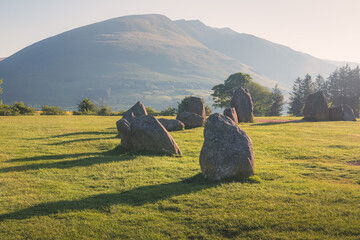 Golden sunrise or sunset light cast across the historic and sacred megalithic site Castlerigg Stone...