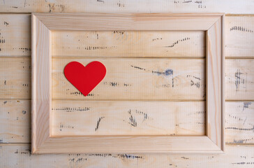 Frame with red hearts on beige wooden background