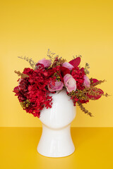 Flower arrangement with dried red flowers with head shaped pot