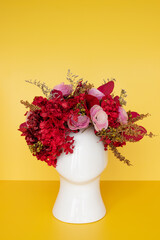 Obraz premium Flower arrangement with dried red flowers with head shaped pot