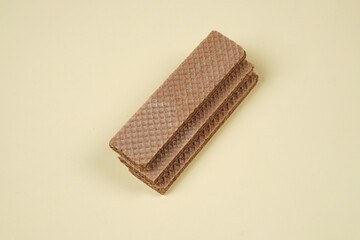 Random pile of wafers isolated on a yellow background. Chocolate biscuit wafers filled with delicious creamy chocolate. Dry and crispy wafers ready to eat. Ready to start the day with a wafer.