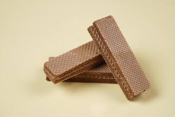 Random pile of wafers isolated on a yellow background. Chocolate biscuit wafers filled with delicious creamy chocolate. Dry and crispy wafers ready to eat. Ready to start the day with a wafer.