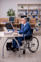 Old businessman employee in wheel-chair working in the office