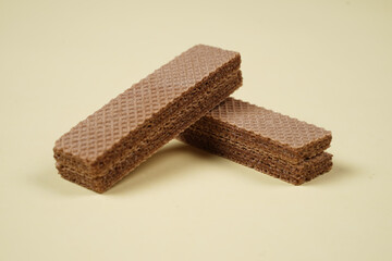 Random pile of wafers isolated on a yellow background. Chocolate biscuit wafers filled with delicious creamy chocolate. Dry and crispy wafers ready to eat. Ready to start the day with a wafer.