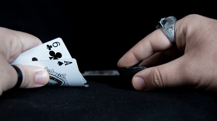 Manos de hombre con anillos jungando al poker