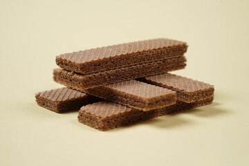 Random pile of wafers isolated on a yellow background. Chocolate biscuit wafers filled with delicious creamy chocolate. Dry and crispy wafers ready to eat. Ready to start the day with a wafer.