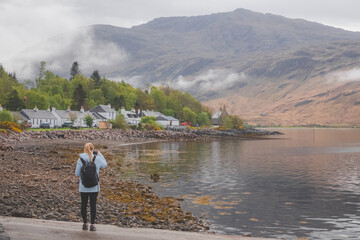 A young female tourist takes a photograph with her smartphone of Inverie village on the remote Knoydart peninsula in the Scottish Highlands, west coast of Scotland.