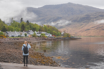 A young female tourist takes a photograph with her smartphone of Inverie village on the remote...