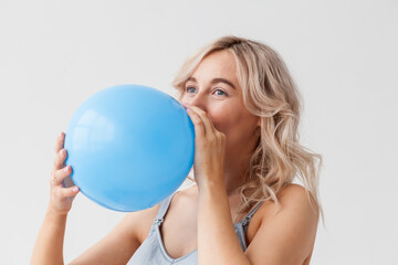 A beautiful young pregnant woman with a big belly in blue jeans holds a balloon that means that a boy will be born.