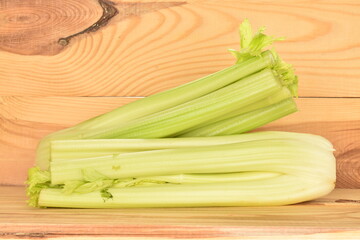 Two light green natural, juicy stalks of celery, close-up, against a background of natural wood.