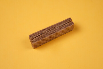 Random pile of wafers isolated on a yellow background. Chocolate biscuit wafers filled with delicious creamy chocolate. Dry and crispy wafers ready to eat. Ready to start the day with a wafer.