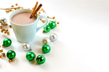 Hot chocolate in teal mug with Christmas ornaments on a white background