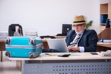 Old male employee preparing for travel in the office