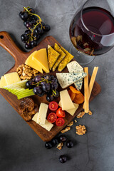 Red Wine And Assorted Cheese Plate with fruit on wooden plate