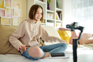 Beautiful teenage girl recording video blog with her smartphone. Young vlogger shooting vlog at home. Teen influencer creating content for her social media account.