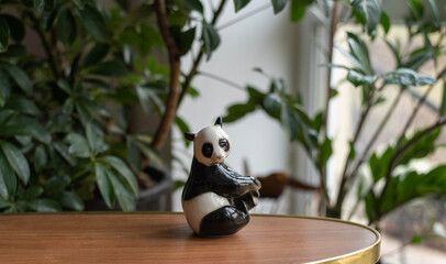 Mid century modern porcelain figurine, panda bear on a wooden table with plants