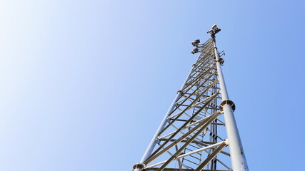 Communication tower base station. Metal structure wireless mobile phone communication transceiver station in 4G and 5G system in bottom view on blue sky background with copy space. Selective focus