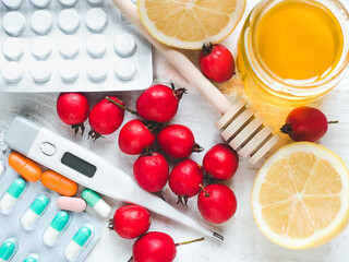 Fresh yellow lemon, jug of honey and red berries on a white wooden table. Top view, close-up, isolated. Concept of preventing colds