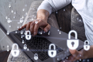 A programmer is typing a code on a keyboard to protect a cyber security from hacker attacks and save clients confidential data. Padlock Hologram icons over the typing hands.