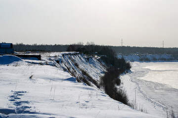 Steep ravine in winter. At the bottom of the ravine is a frozen river. Winter landscape
