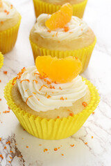closeup of vanilla buttercream cupcakes with orange slice