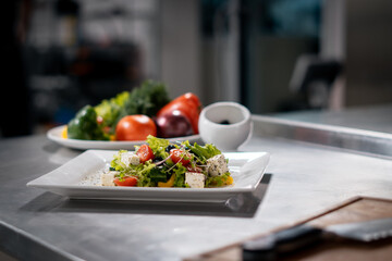 fresh greek salad with tomato, lettuce and feta cheese at restaurant kitchen