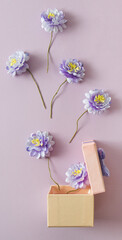 Blue flowers getting out from gift box. Violet back graund.