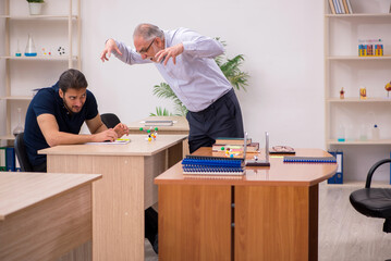 Old male teacher and young male student in the classroom