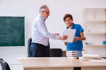 Old male teacher and schoolboy in the classroom