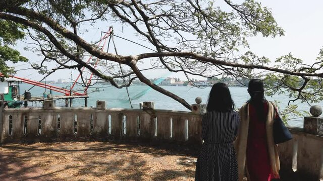 Tourists Indian Mother and daughter walking along the sea shore in Fort Kochi beach on summer vacation Kerala India 4K slow motion video footage. outing  in coastal region walkway.