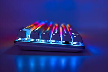 Backlit keyboard. Gaming keyboard with RGB light, side view. Colorful keyboard in neon light