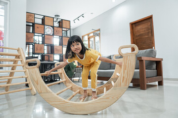 little girl alone while playing balance in the pikler triangle toy in the living room