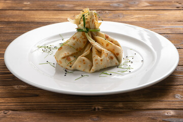 Vegetarian pancake with a filling in the form of a bag tied with green onions.