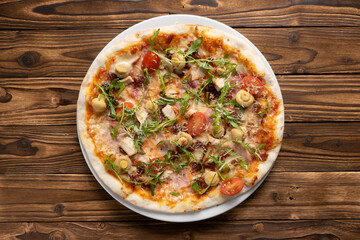Pizza with bacon, chicken, mushrooms, arugula, tomatoes and mozzarella cheese